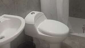 A bathroom with a toilet, bidet, and a shower curtain.