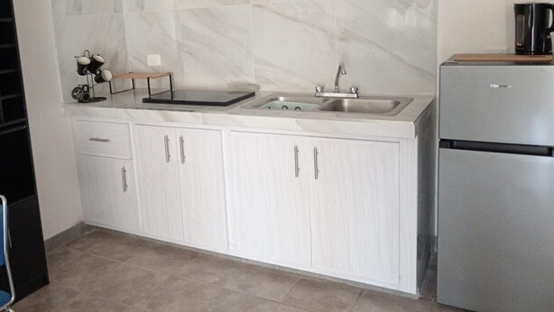 A kitchen with white cabinets, a stainless steel sink, and a refrigerator.