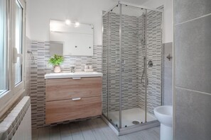 A modern bathroom with a glass shower enclosure, a sink with a mirror, and a toilet.
