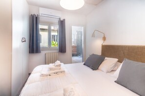 A hotel room with a bed, a window with curtains, an air conditioning unit, and a wall-mounted lamp. - Laura Roof Terrace Teatro dell'Opera (Roma)