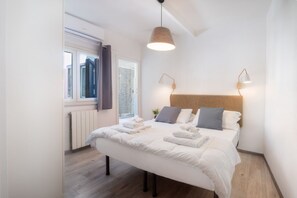 A bedroom with a bed, bedside lamps, a window, and a radiator.