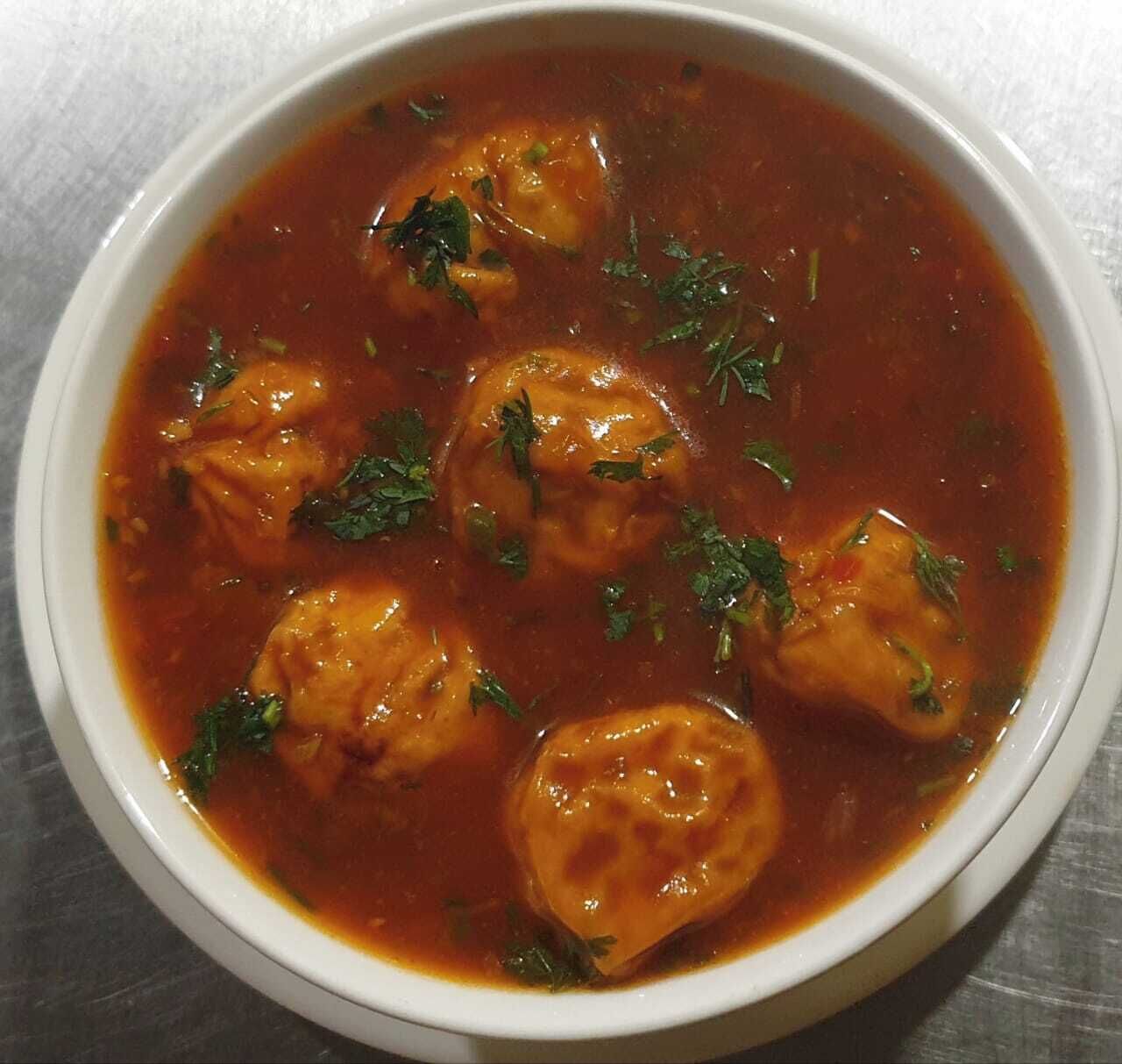 A bowl of soup with dumplings and herbs.