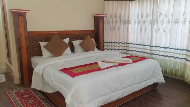 Una cama bien hecha con cabecera de madera, colcha y manta rojo y blanco.