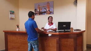 Un mostrador de recepción con una computadora, un calendario y un cuadro enmarcado de un puente.