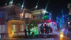 Un edificio de dos pisos con balcones, una entrada bien iluminada y una decoración festiva con luces y globos.