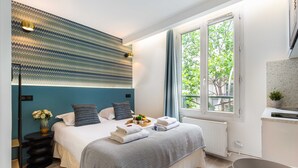Camera da letto moderna con un letto, comodino e finestra vista verde.