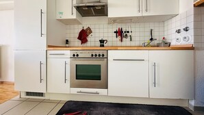 Een moderne keuken met witte kasten, een roestvrijstalen afzuigkap en een betegelde spatwand.