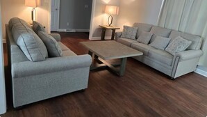 A living room with two grey sofas, a wooden coffee table, and two lamps.