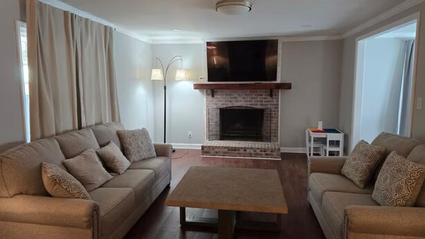 A living room with two sofas, a coffee table, a fireplace, and a TV mounted above it.