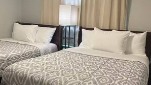 A hotel room with two beds, each with patterned bedding and white pillows.