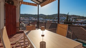 Un balcon avec une table, des chaises et une lampe.