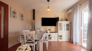 Un coin repas avec une table dressée pour quatre personnes, un téléviseur fixé au mur et un meuble avec des portes en verre.