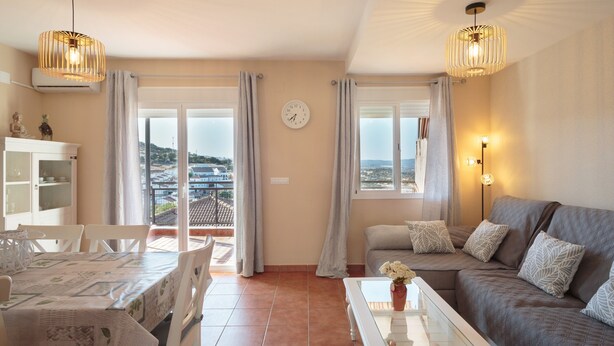Un salon comprenant un canapé, une table à manger, des chaises et un balcon avec des rideaux.