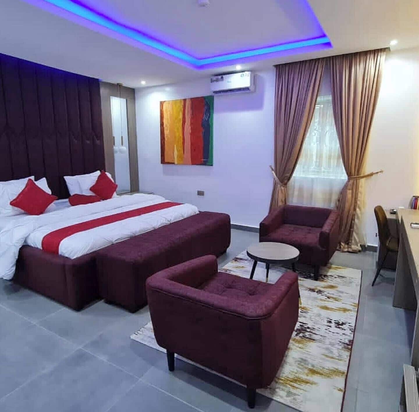 Una habitación de hotel moderna con una cama grande, un sofá, una mesita y un escritorio.