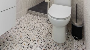 Un baño pequeño con inodoro blanco, un cesto de basura y un porta papel higiénico.