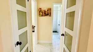 A hallway with white doors with frosted glass panels, a marble floor, and a painting on the wall. - The 98 House Minutes from WEC, OBS, FAST & HITS. Located off of W HWY 40! (Ocala)
