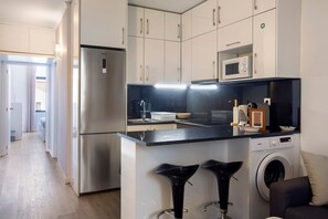 A modern kitchen with a built-in washing machine, a microwave, and a stainless steel refrigerator. - Apartment 'Refúgio Na Cidade 104' with Wi-Fi (Funchal)