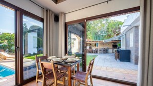 A dining area with a table and chairs, a pool, and a view of a backyard with a barbecue area. - 'Guest Apartment with Private Pool, Wi-Fi and Air Conditioning' (Roquetas de Mar)