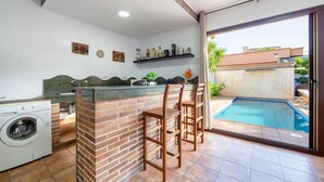 A kitchen with a washing machine, a brick counter, and a pool visible through the glass door. - 'Guest Apartment with Private Pool, Wi-Fi and Air Conditioning' (Roquetas de Mar)