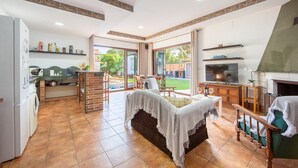 A spacious living area with a sofa, a TV, and a fireplace. There is a kitchen area with a washing machine and a dining area with a table and chairs. - 'Guest Apartment with Private Pool, Wi-Fi and Air Conditioning' (Roquetas de Mar)