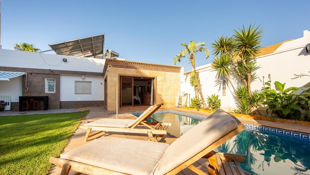 A poolside area with lounge chairs, a small building with a door, and a solar panel. - 'Guest Apartment with Private Pool, Wi-Fi and Air Conditioning' (Roquetas de Mar)