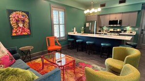 Une cuisine moderne dotée d’un îlot central, de tabourets de bar et d’un coin repas agrémenté d’un tapis coloré.