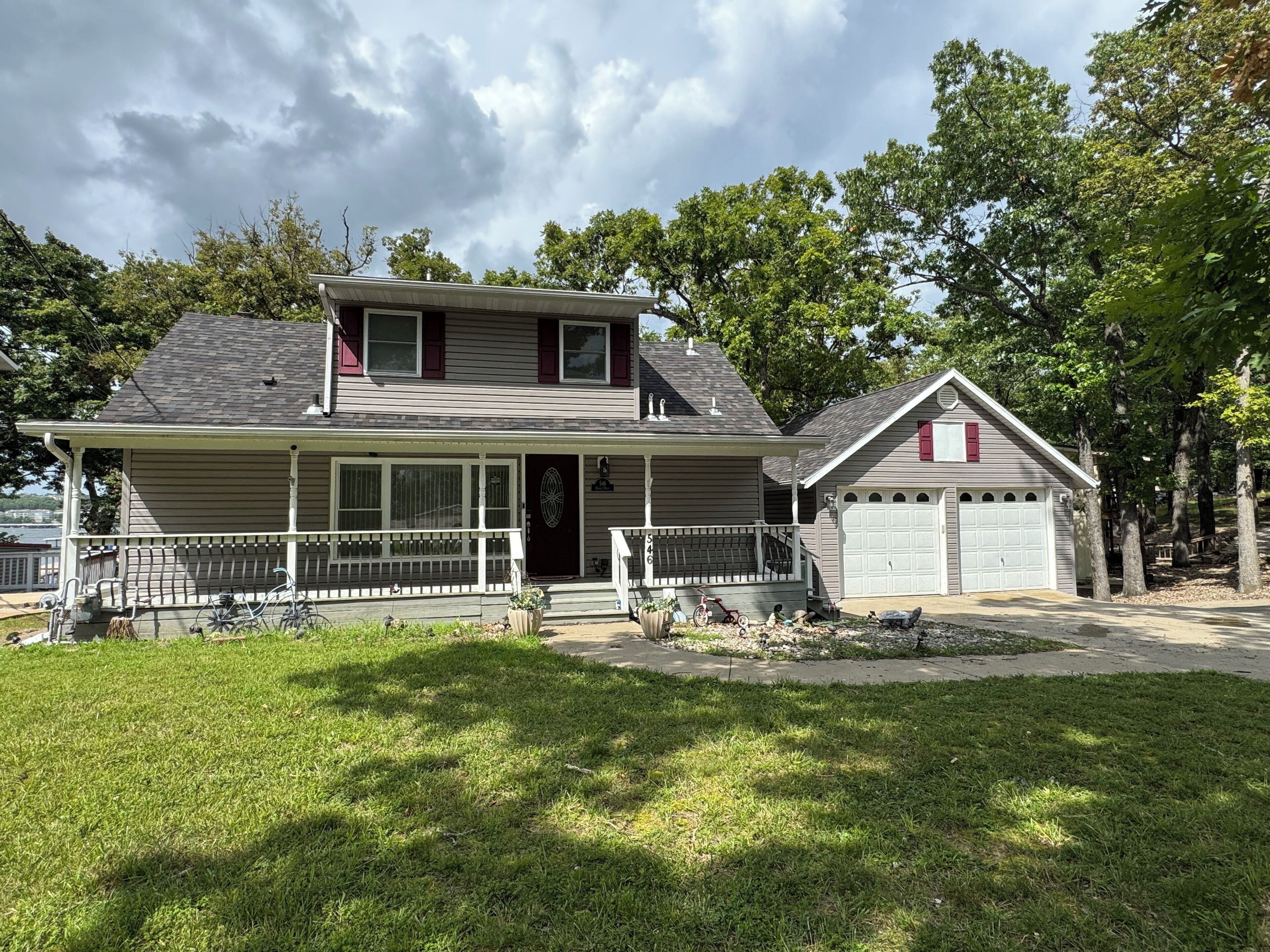A two-story house with a front porch, a garage, and a lawn.