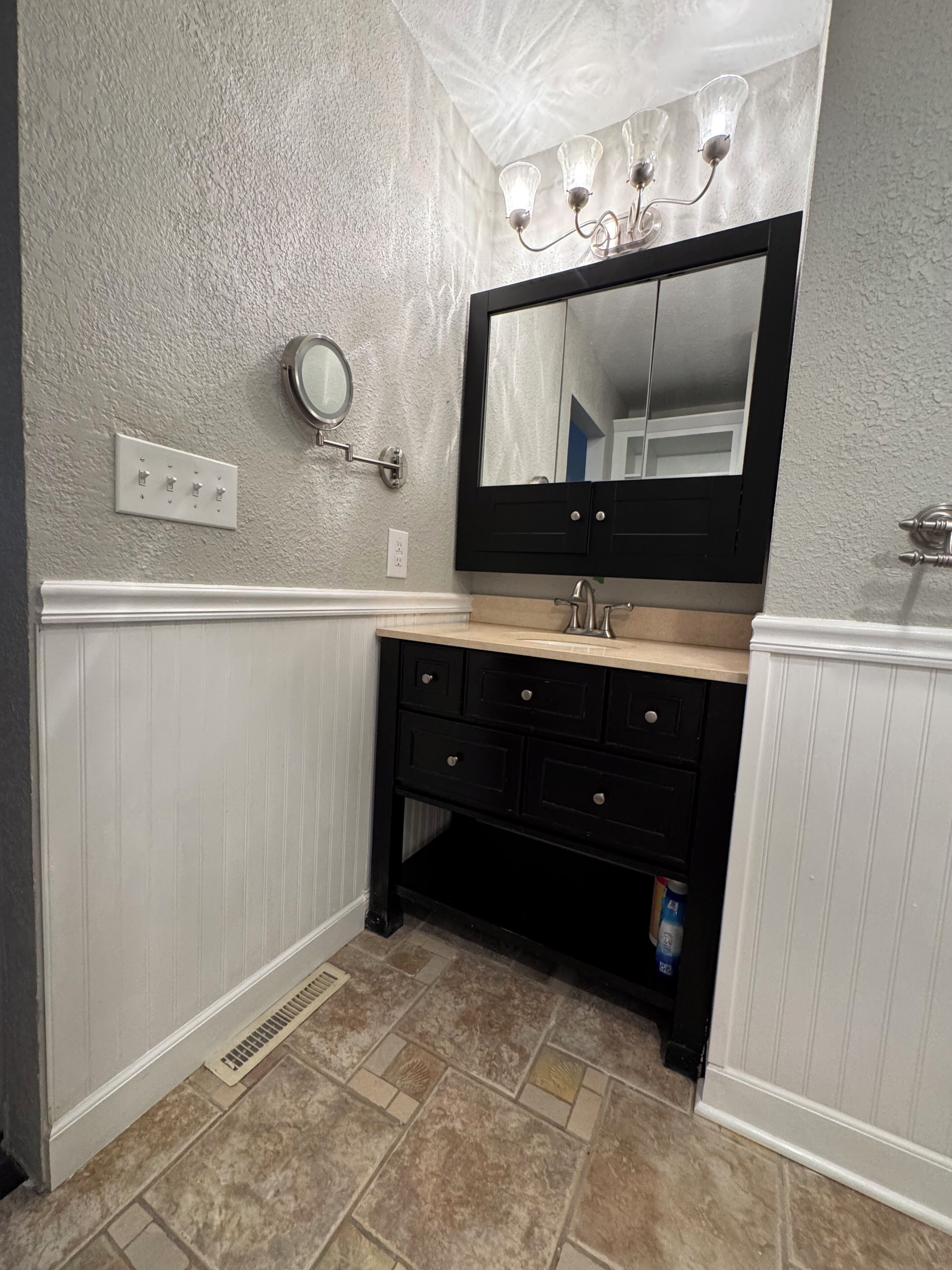 A bathroom with a vanity, a mirror, and a light fixture.