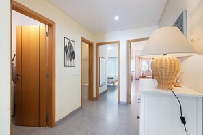 Ein Korridor mit Holztüren, einem weißen Schrank mit Lampe und einem gerahmten Bild an der Wand.