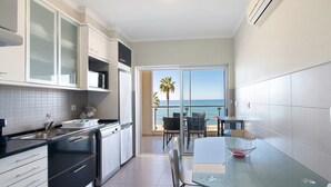 Une cuisine moderne avec un coin repas, de grandes fenêtres et une vue sur la mer.