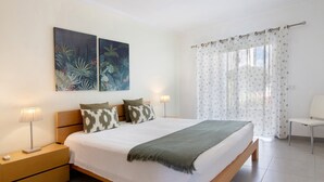 Une chambre à coucher comprenant un lit, des tables de chevet, une chaise et deux tableaux accrochés au mur.
