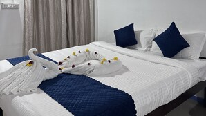 Une chambre d’hôtel avec un lit, un ventilateur de plafond, une fenêtre avec des rideaux et un luminaire fixé au mur.
