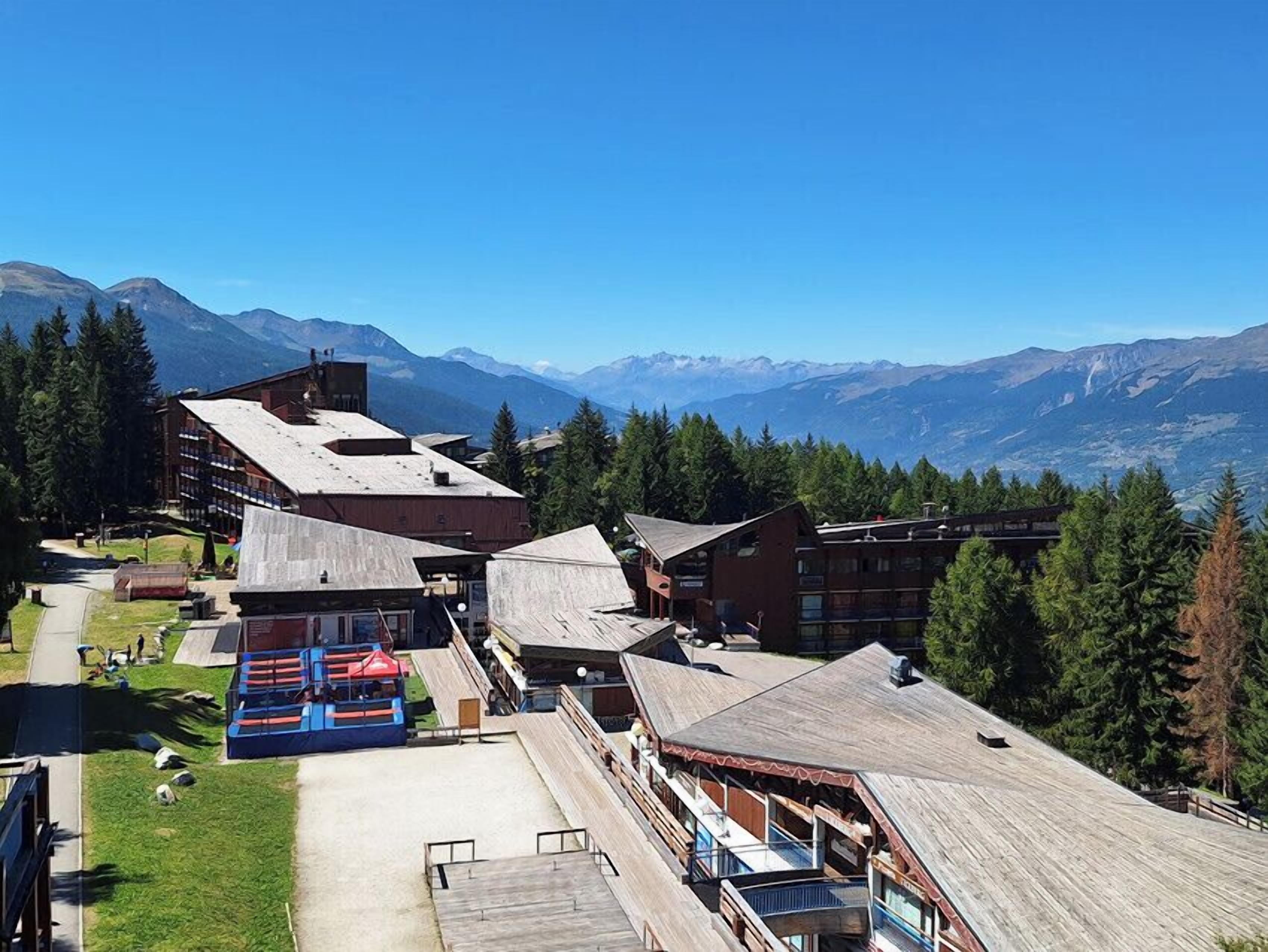 A lodge with multiple buildings, a ski lift, and a mountainous backdrop.
