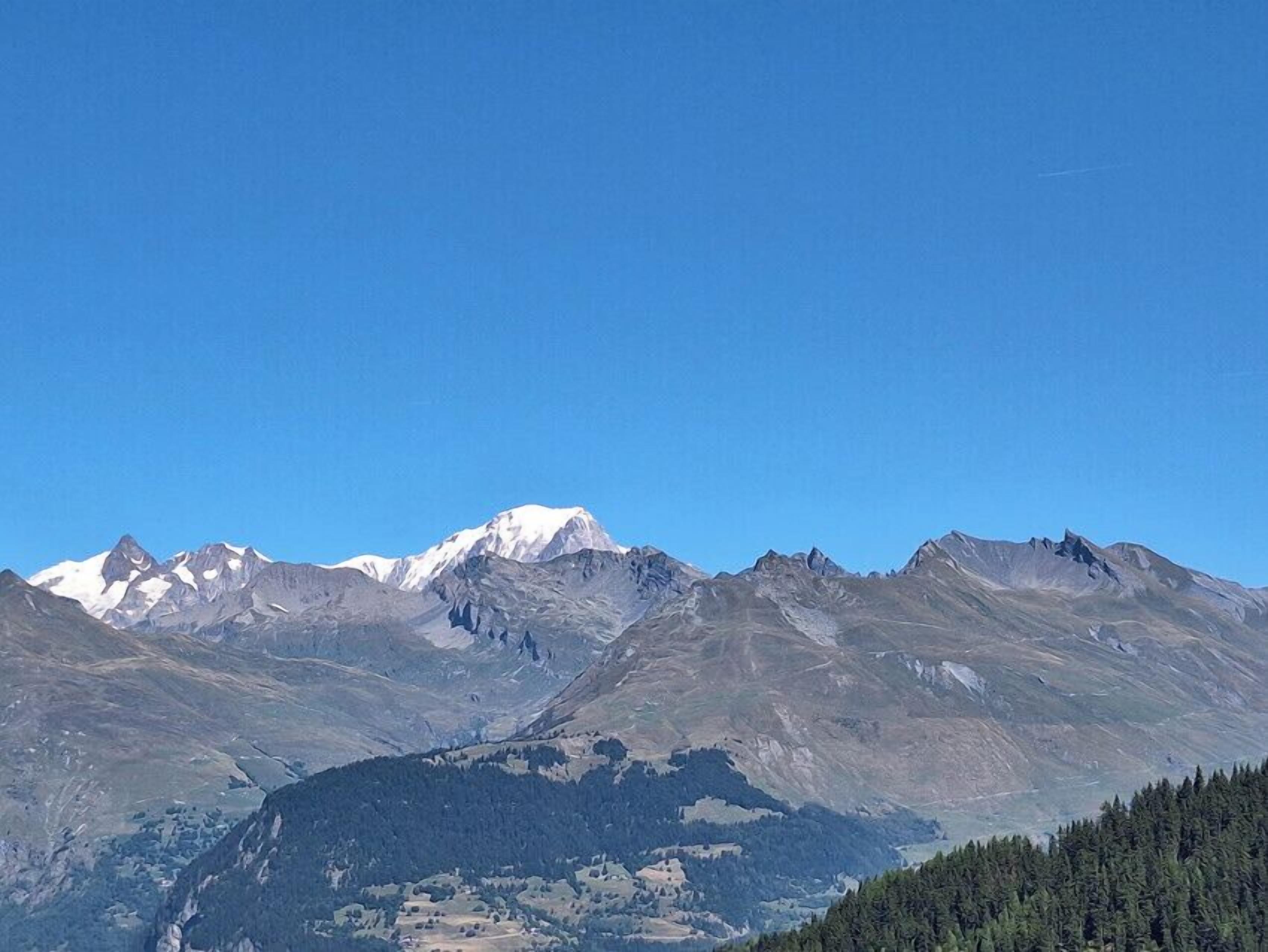 Paisaje montañoso con picos nevados y un valle en la parte baja.