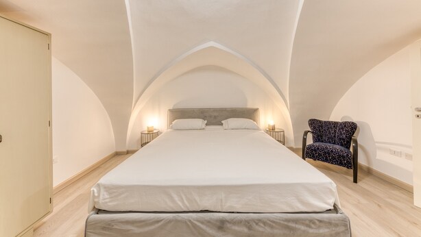 Une chambre avec un grand lit, une chaise et une fenêtre de toit.