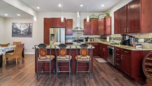Una cocina moderna con armarios de madera oscura, un refrigerador de acero inoxidable y una isla central con taburetes de bar.