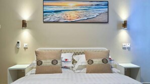 A hotel room with a bed, two bedside tables, a painting of a beach scene, and two wall-mounted light fixtures.