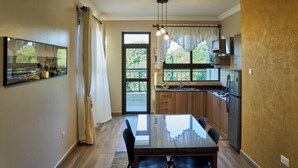 Een moderne keuken met een eethoek, grote ramen en uitzicht op groen.
