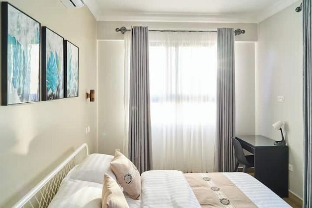 Una habitación de hotel con cama, escritorio y ventana con cortinas.