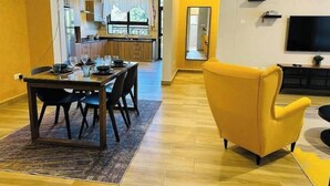 Een moderne woonkamer met een eethoek, gele wanden en een gele fauteuil.