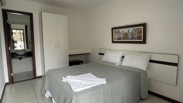 A bedroom with a bed, a wardrobe, a bathroom, and a painting on the wall.