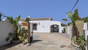 A white building with a tiled roof, a gated entrance, and potted plants. - Casa Pepe: Rural Home with Pool & Air Conditioning in Conil (Conil de la Frontera)