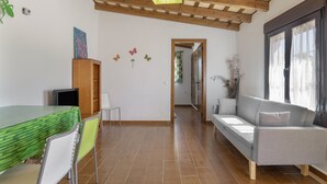 A room with a dining table, chairs, a sofa, a TV, and a ceiling fan. - Casa Pepe: Rural Home with Pool & Air Conditioning in Conil (Conil de la Frontera)