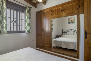 A bedroom with a bed, wooden wardrobe, and a window with curtains.