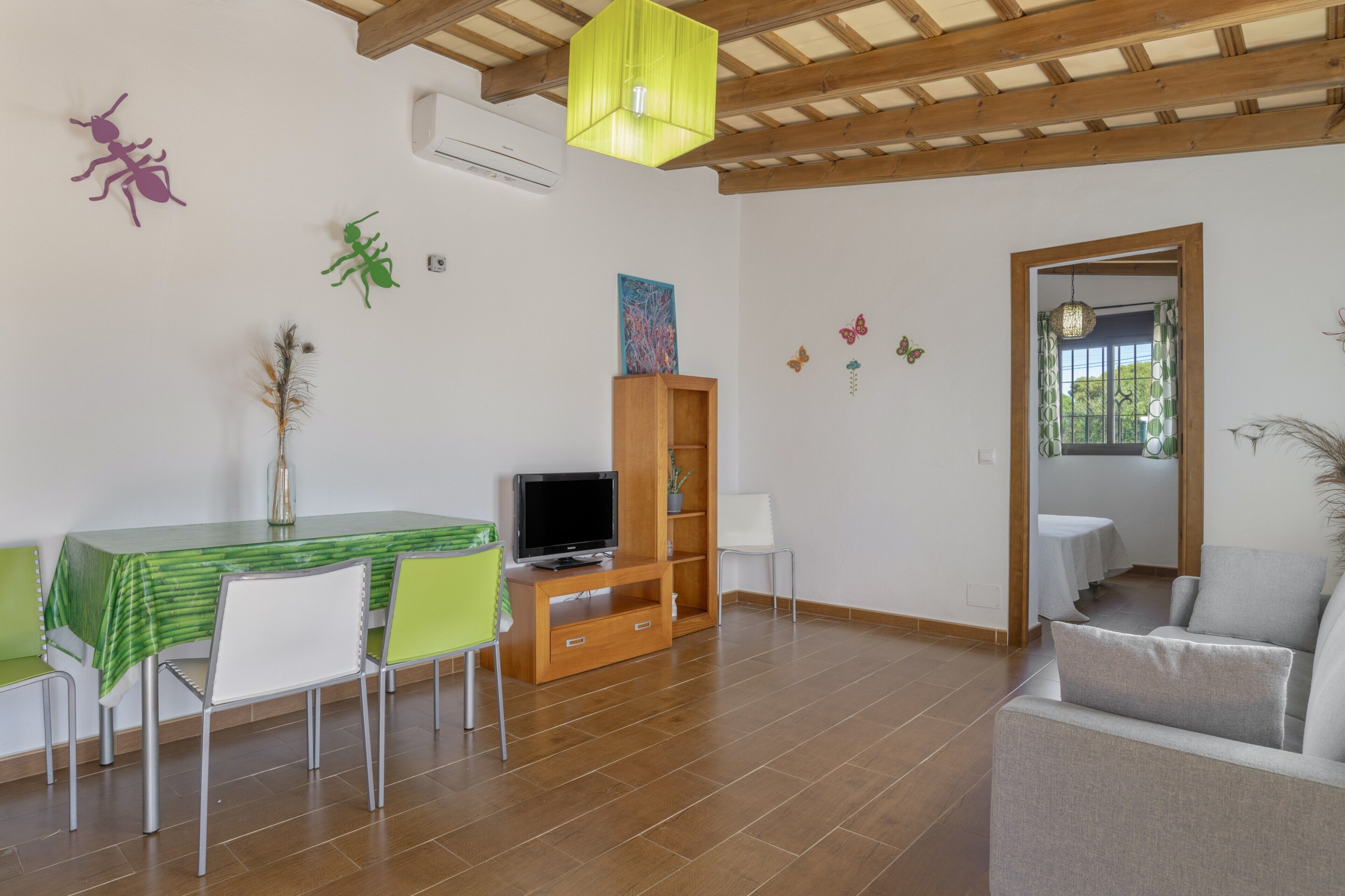 Uma área de refeições com mesa, cadeiras, televisão e estante.