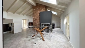 A spacious kitchen with a brick wall, a modern stove, and a glass dining table with chairs. - Reel House - Affitti Brevi Italia (Lecco)
