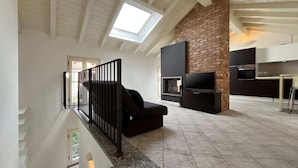 A spacious living area with a high ceiling, a fireplace, and a modern kitchen. - Reel House - Affitti Brevi Italia (Lecco)