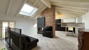 A spacious living area with a fireplace, a TV, and a kitchen in the background. - Reel House - Affitti Brevi Italia (Lecco)