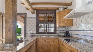 Een kleine keuken met houten kastjes, een ingebouwde kookplaat en een raam met uitzicht op de omgeving.
