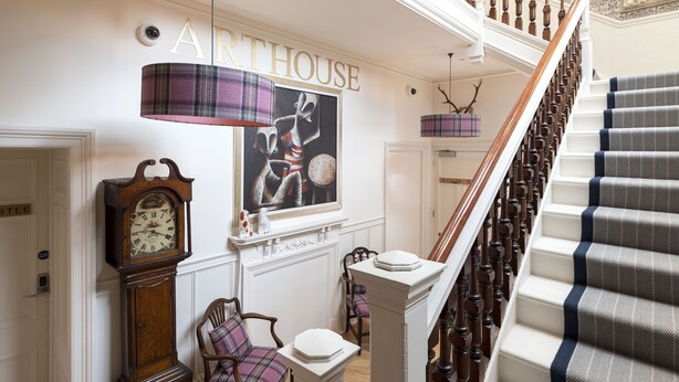 A grand staircase with a checkered carpet, a wall-mounted clock, and a fireplace with a mantelpiece. - Scottish Thistle - 1 bedroom with optional sofa bed (Inverness)